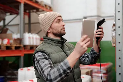 Warehouse worker checking stock with a tablet and barcode scanner