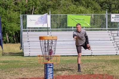 Disc golf player throwing towards a basket at a tournament