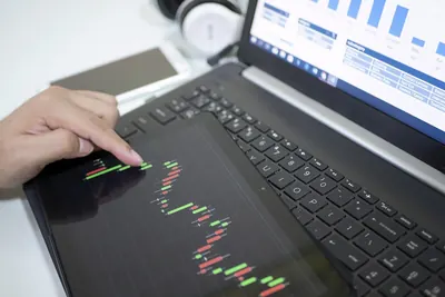 Trader analysing candlestick charts on a laptop and tablet