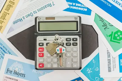 Calculator and house keys on top of mortgage leaflets