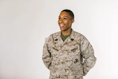 Smiling female service member in a camouflage uniform