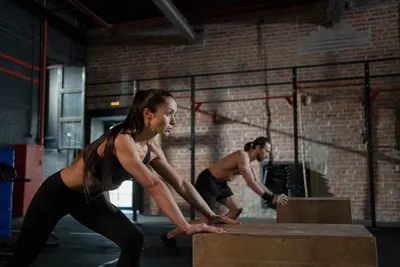 Woman performing a step-up onto a box during a functional training session in a bright gym