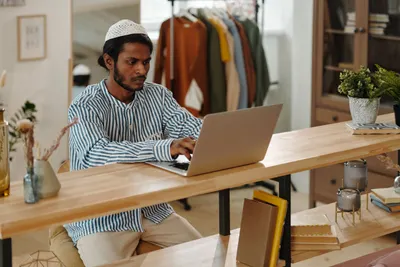 Person working at a laptop in a bright home office, reviewing software on screen