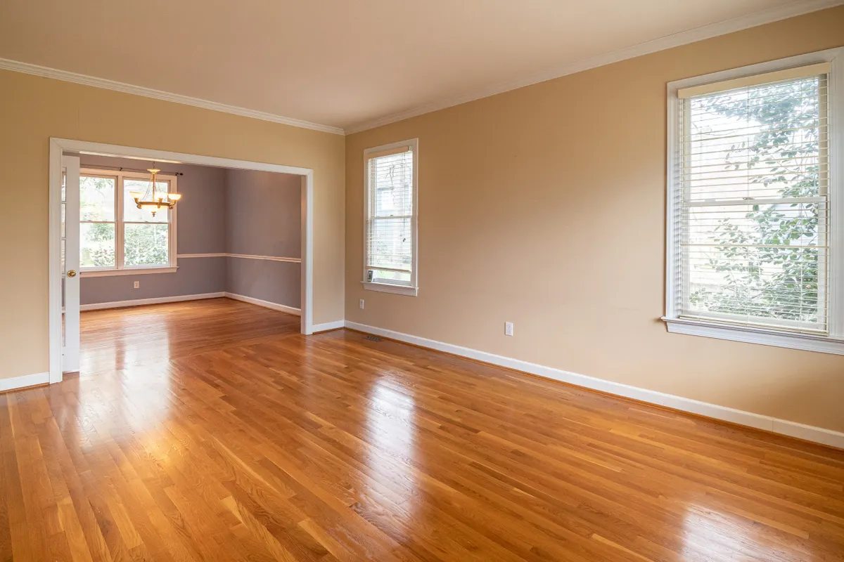 Empty living room with daylight falling across a warm hardwood floor