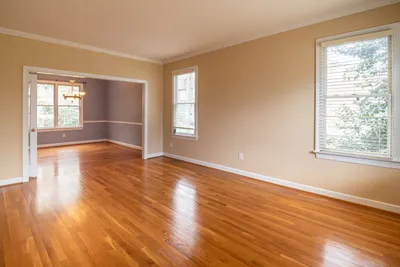 Empty living room with daylight falling across a warm hardwood floor