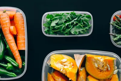 Food storage containers filled with carrots, spinach and pumpkin