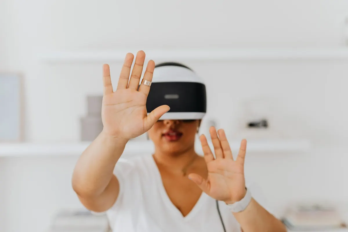Person wearing a head-mounted display and reaching out with both hands